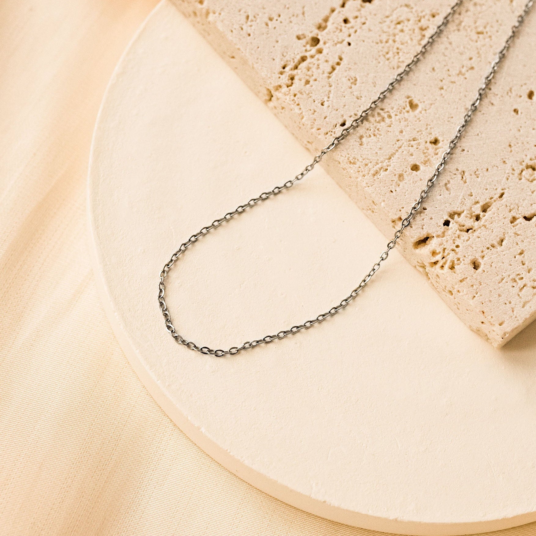 Silver chain anklet on a beige background