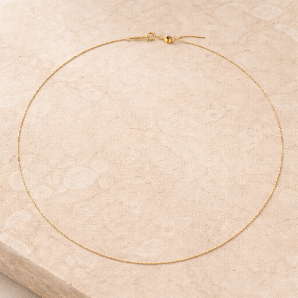 Gold necklace on a textured beige surface