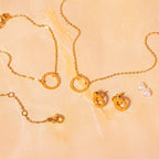 Gold necklace, bracelet and earrings on a beige background