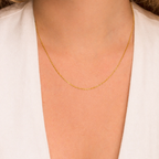 Gold chain necklace on a person wearing a white shirt