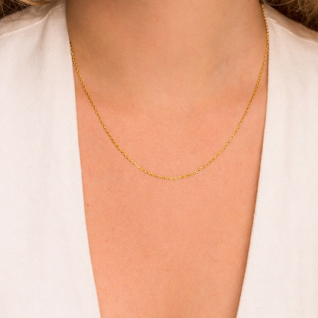 Gold chain necklace on a person wearing a white shirt