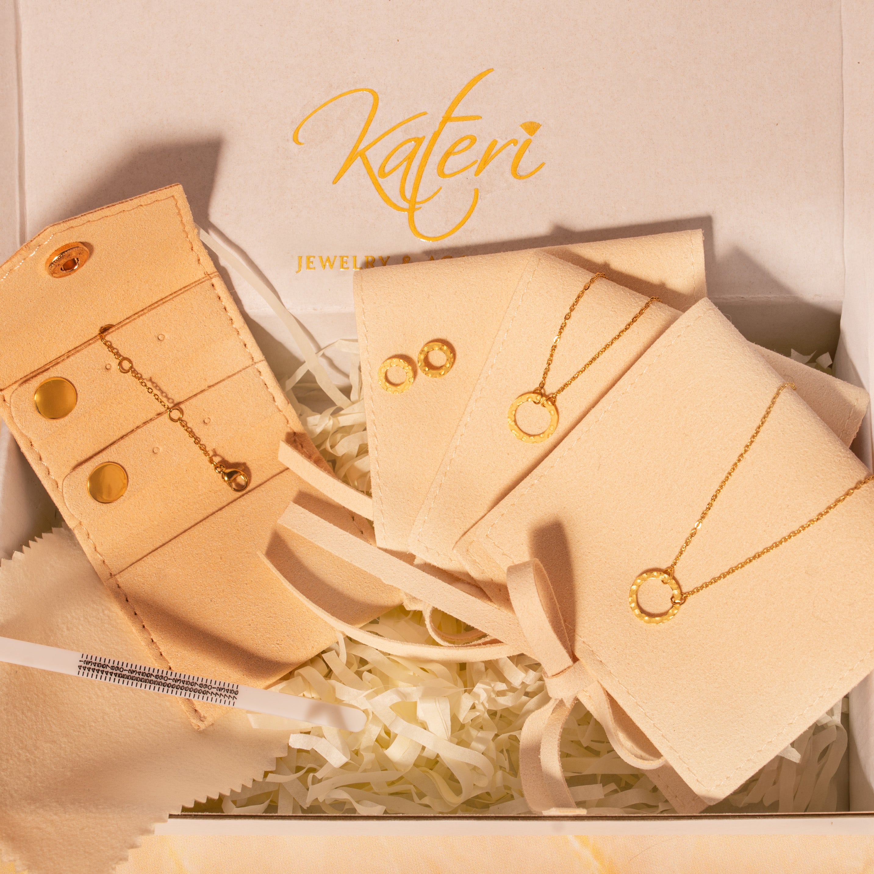 Beige jewelry set with necklaces, bracelet and earrings in a gift box on a marble surface.